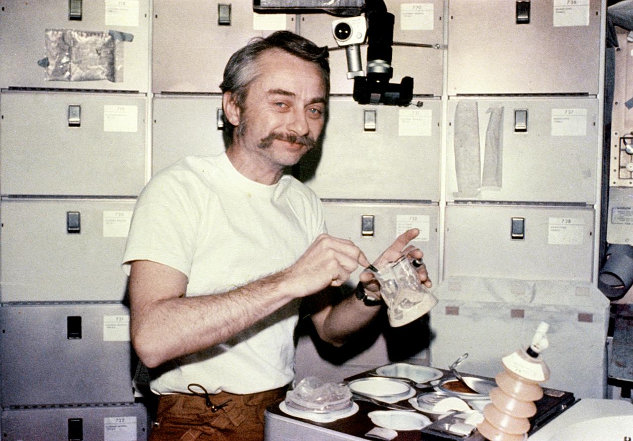 This photograph was taken during the Skylab-3 mission (2nd marned mission), showing Astronaut Owen Garriott enjoying his meal in the Orbital Workshop crew wardroom. The tray contained heating elements for preparing the individual food packets. The food on Skylab was a great improvement over that on earlier spaceflights. It was no longer necessary to squeeze liquified food from plastic tubes. Skylab's kitchen was so equipped that each crewman could select his own menu and prepare it to his own taste.