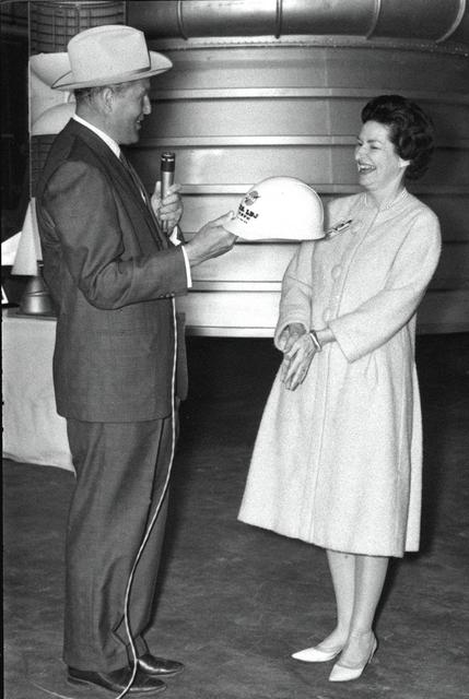 Marshall Space Flight Center Director Dr. Wernher von Braun presents Lady Bird Johnson with an inscribed hard hat during the First Lady's March 24, 1964 visit. While at the Marshall Center, Mrs. Johnson addressed Center employees, toured facilities and witnessed test firings of a Saturn I first stage and an F-1 engine. Dr. von Braun is wearing a Texas hat presented to him months earlier by Lyndon Johnson during a visit to the Johnson ranch in Texas. 