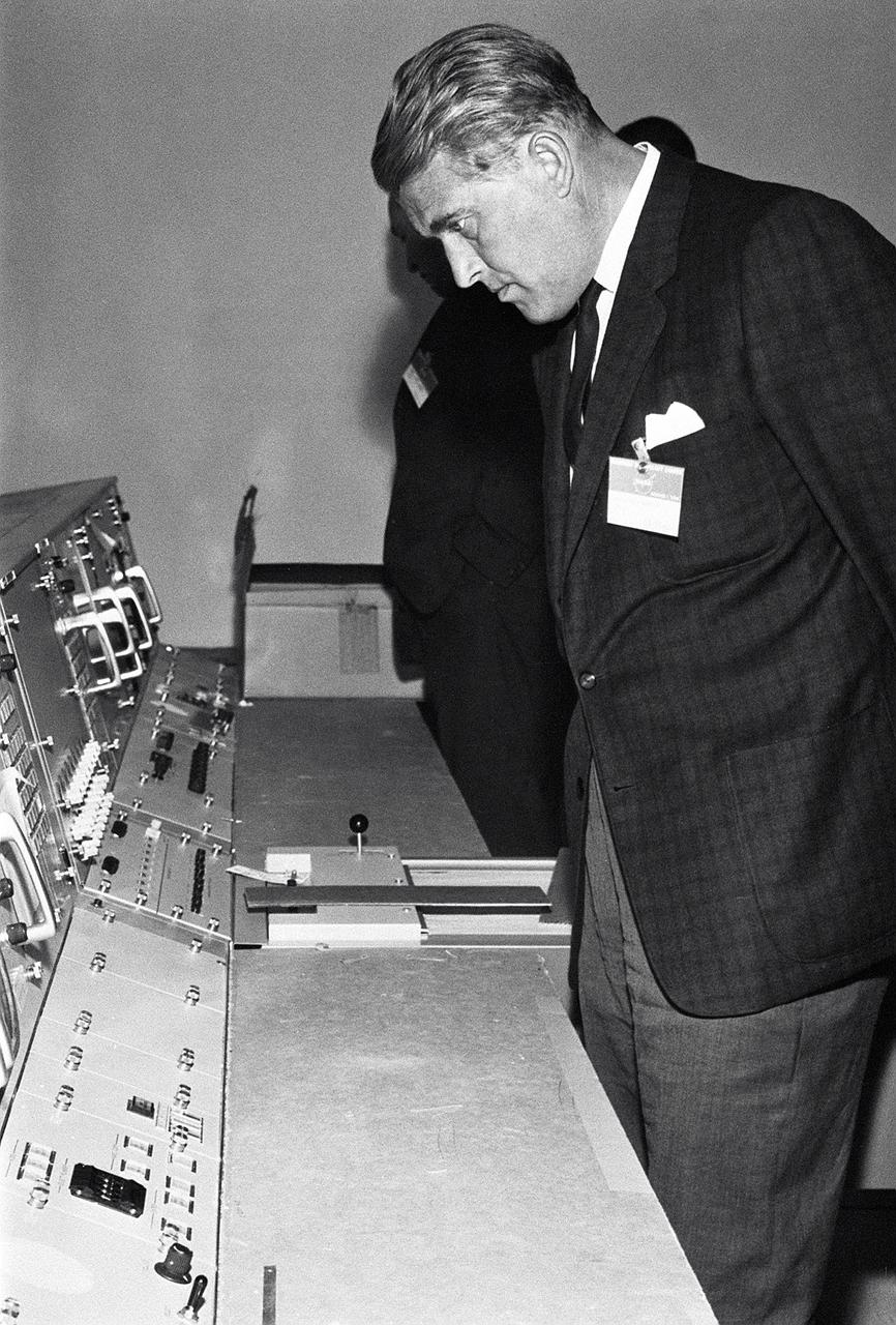 This photograph, dated October 14, 1964, was taken at the Marned Spacecraft Center, now the Johnson Space Center in Houston, Texas. Dr. von Braun is shown looking over consoles in the Manned Spaceflight Control Center.