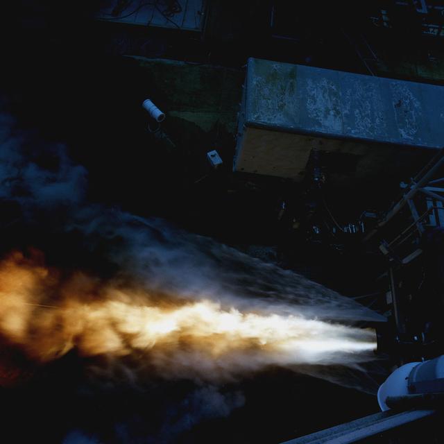 This shot offers a bird's eye-view of a Fastrac II engine duration test at Marshall's Test Stand 116. The Fastrac II engine was designed as a part of the low cost X-34 Reusable Launch Vehicle (RLV). The purpose for these tests was to test the different types of metal alloys in the nozzle. Beside the engine were six additional nozzels which spray a continuous stream of water onto the test stand to reduce damage to the test stand and the engines. The X-34 program was cancelled in 2001.