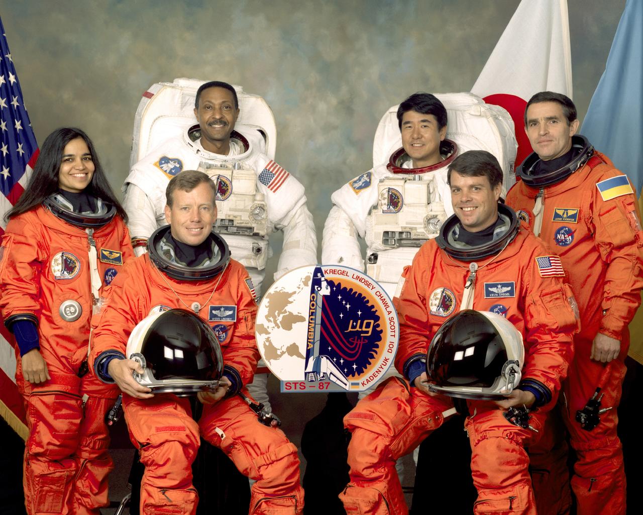 Five astronauts and a payload specialist take a break from training at the Johnson Space Center (JSC) to pose for the STS-87 crew portrait. Wearing the orange partial pressure launch and entry suits, from the left, are Kalpana Chawla, mission specialist; Steven W. Lindsey, pilot; Kevin R. Kregel, mission commander; and Leonid K. Kadenyuk, Ukrainian payload specialist. Wearing the white Extravehicular Mobility Unit (EMU) space suits are mission specialists Winston E. Scott (left) and Takao Doi (right). Doi represents Japan’s National Space Development Agency (NASDA). The STS-87 mission launched aboard the Space Shuttle Columbia on November 19, 1997. The primary payload for the mission was the U.S. Microgravity Payload-4 (USMP-4).