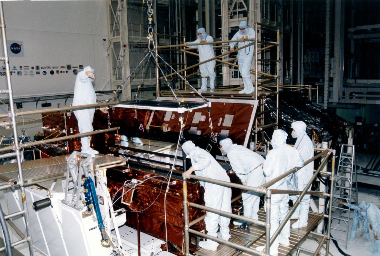KENNEDY SPACE CENTER, FLORIDA  STS-82 PREPARATIONS VIEW --- Payload processing workers in the Kennedy Space Center (KSC) Vertical Processing Facility (VPF) prepare to integrate the Space Telescope Imaging Spectrograph (STIS), suspended at center, into the Orbiter Replacement Unit (ORU) Carrier and Scientific Instrument Protective Enclosure (SIPE).  STIS will replace the Goddard High Resolution Spectrograph (GHRS) on the Hubble Space Telescope (HST).  Four of the seven STS-82 crew members will perform a series of spacewalks to replace two scientific instruments with two new instruments, including STIS, and perform other tasks during the second HST servicing mission.  HST was deployed nearly seven years ago and was initially serviced in 1993. 