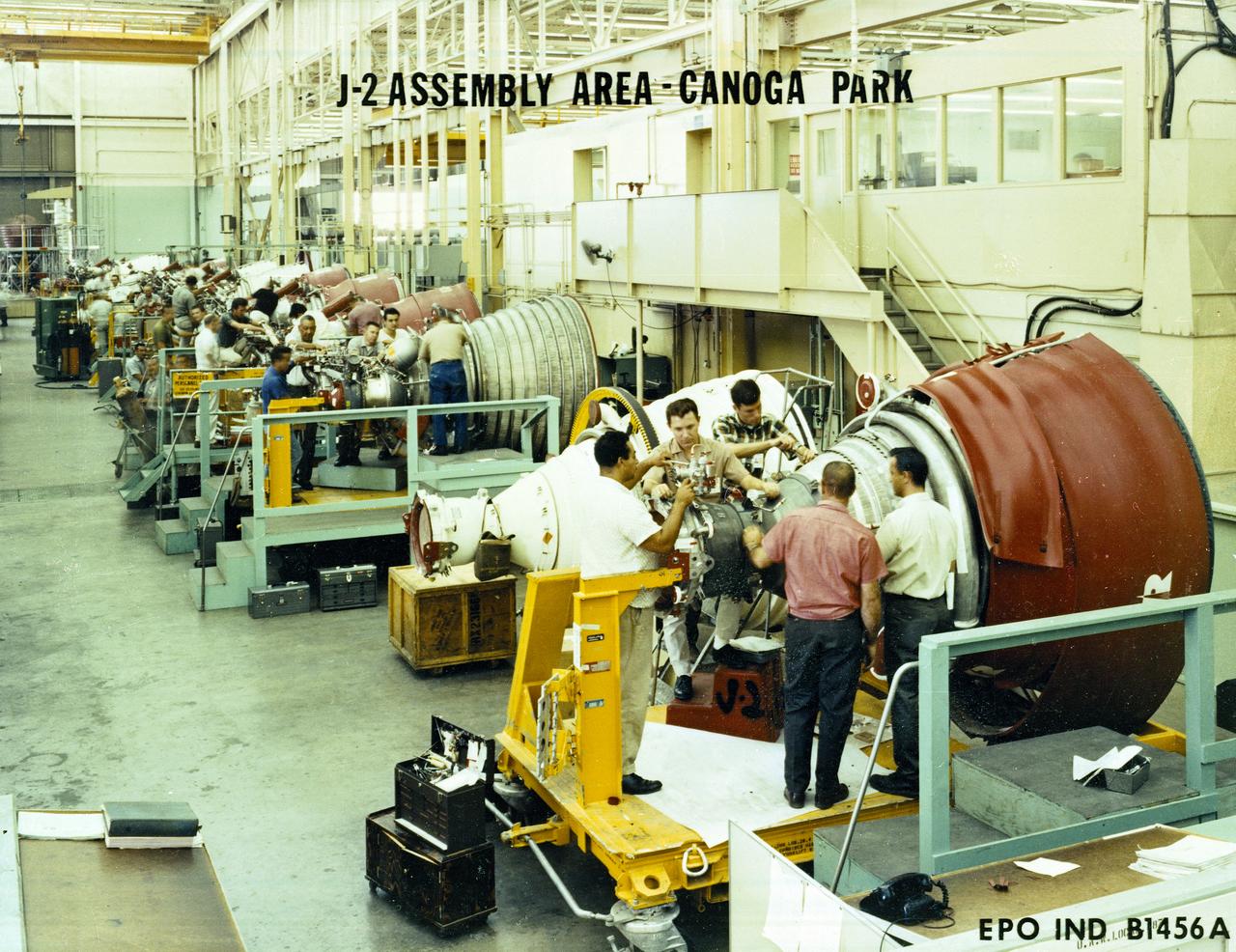 Workmen inspect a J-2 engine at Rocketdyne's Canoga Park, California production facility. The J-2, developed under the direction of the Marshall Space Flight Center, was propelled by liquid hydrogen and liquid oxygen. A single J-2 engine was used in the S-IVB stage (the second stage of the Saturn IB and third stage for the Saturn V) and a cluster of five J-2 engines was used to propel the second stage of the Saturn V, the S-II. Initially rated at 200,000 pounds of thrust, the J-2 engine was later uprated in the Saturn V program to 230,000 pounds.