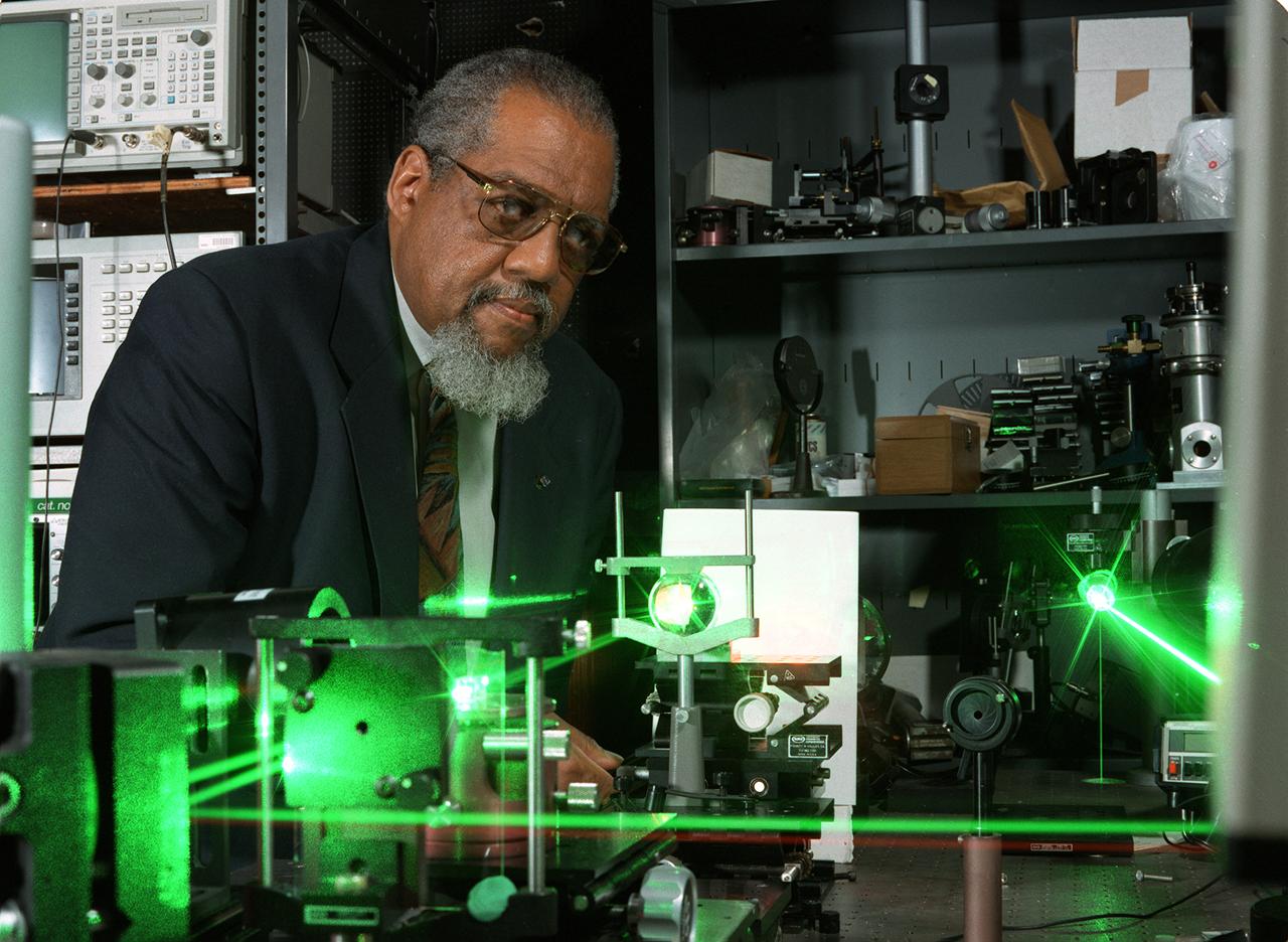 NASA research Dr. Donald Frazier uses a blue laser shining through a quartz window into a special mix of chemicals to generate a polymer film on the inside quartz surface. As the chemicals respond to the laser light, they adhere to the glass surface, forming opticl films. Dr. Frazier and Dr. Mark S. Paley developed the process in the Space Sciences Laboratory at NASA's Marshall Space Flight Center in Huntsville, AL. Working aboard the Space Shuttle, a science team led by Dr. Frazier formed thin-films potentially useful in optical computers with fewer impurities than those formed on Earth. Patterns of these films can be traced onto the quartz surface. In the optical computers on the future, these films could replace electronic circuits and wires, making the systems more efficient and cost-effective, as well as lighter and more compact. Photo credit: NASA/Marshall Space Flight Center