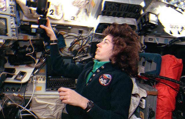 Space Shuttle Discovery (STS-56) Mission Specialist 3 (MS3) Ellen Ochoa handles a 35mm camera on the aft flight deck of the Orbiter. Ochoa is positioned next to the payload station and behind the commander's station.