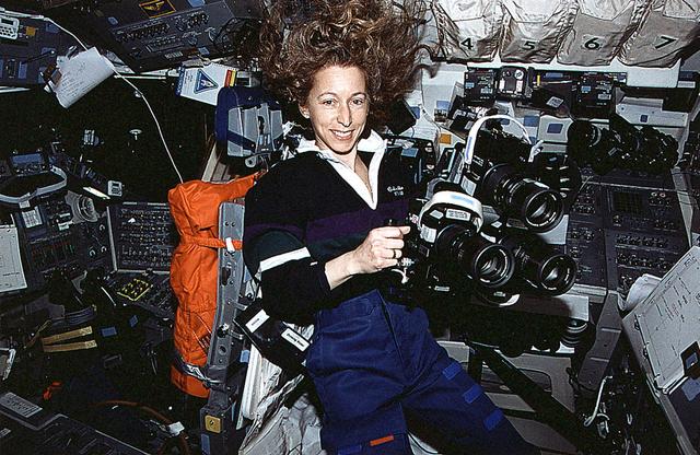 Astronaut Marsha S. Ivins, mission specialist, prepares to aim three Hasselblad cameras through the overhead windows of the Earth-orbiting Space Shuttle Columbia. The three cameras were allowed to simultaneously record the same imagery on different types of film.