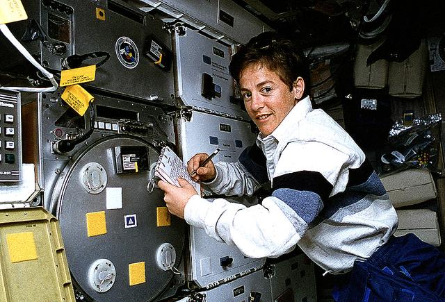 Astronaut Wendy B. Lawrence, flight engineer and mission specialist for STS-67, scribbles notes on the margin of a checklist while monitoring an experiment on the Space Shuttle Endeavour's mid-deck. The experiment is the Protein Crystal Growth (PCG), which takes up locker space near the Commercial Materials Dispersion Apparatus Instruments Technology Associates Experiment (CMIX).