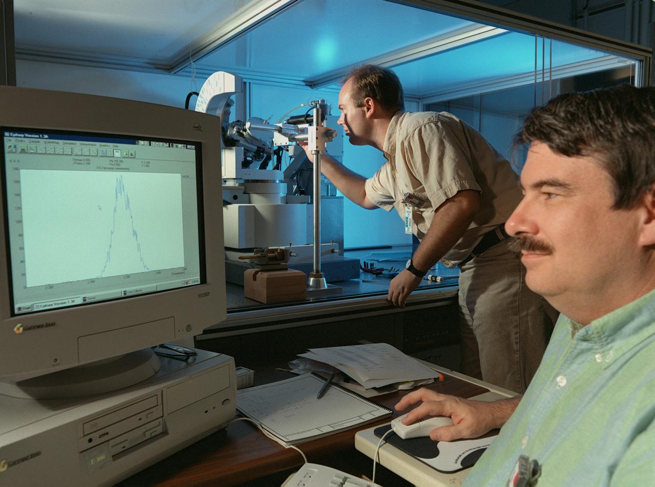 Eddie Snell (standing), Post-Doctoral Fellow the National Research Council (NRC),and Marc Pusey of Marshall Space Flight Center (MSFC) use a reciprocal space mapping diffractometer for marcromolecular crystal quality studies. The diffractometer is used in mapping the structure of marcromolecules such as proteins to determine their structure and thus understand how they function with other proteins in the body. This is one of several analytical tools used on proteins crystalized on Earth and in space experiments. Photo credit: NASA/Marshall Space Flight Center (MSFC)