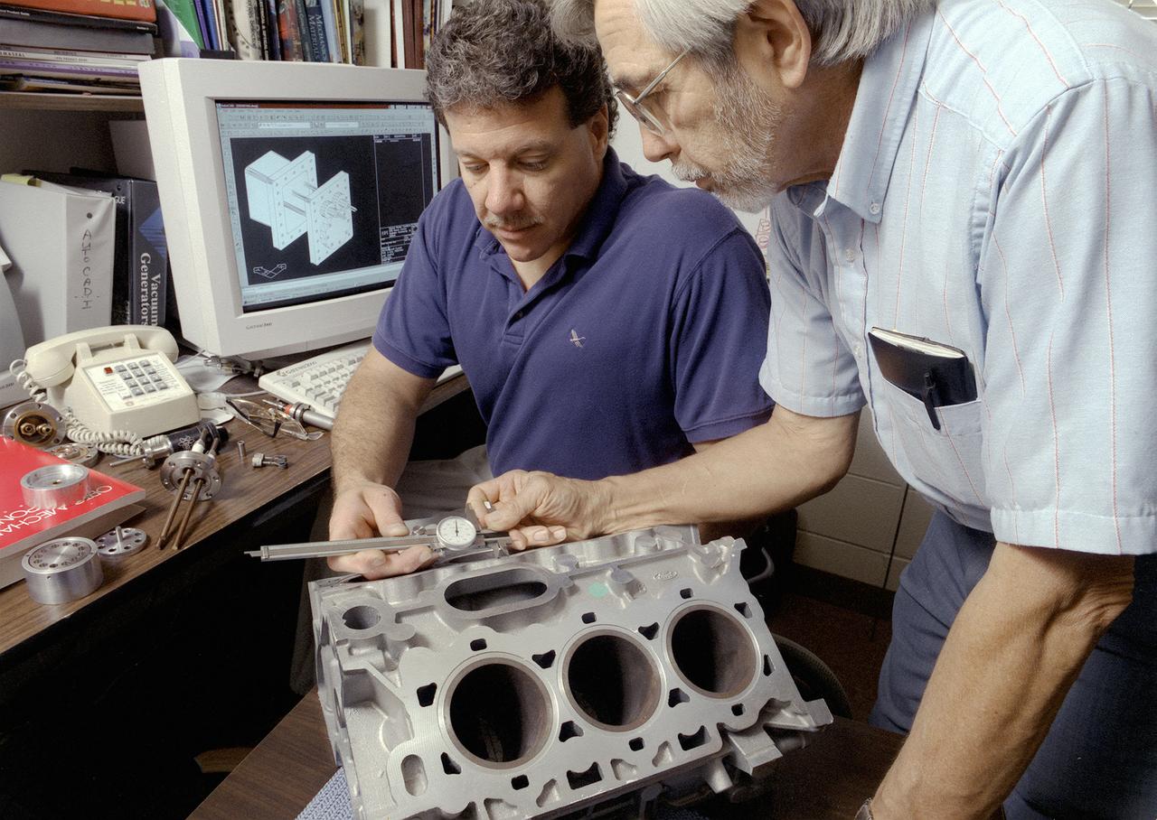 Don Sirois, an Auburn University research associate, and Bruce Strom, a mechanical engineering Co-Op Student, are evaluating the dimensional characteristics of an aluminum automobile engine casting. More accurate metal casting processes may reduce the weight of some cast metal products used in automobiles, such as engines. Research in low gravity has taken an important first step toward making metal products used in homes, automobiles, and aircraft less expensive, safer, and more durable. Auburn University and industry are partnering with NASA to develop one of the first accurate computer model predictions of molten metals and molding materials used in a manufacturing process called casting. Ford Motor Company's casting plant in Cleveland, Ohio is using NASA-sponsored computer modeling information to improve the casting process of automobile and light-truck engine blocks.