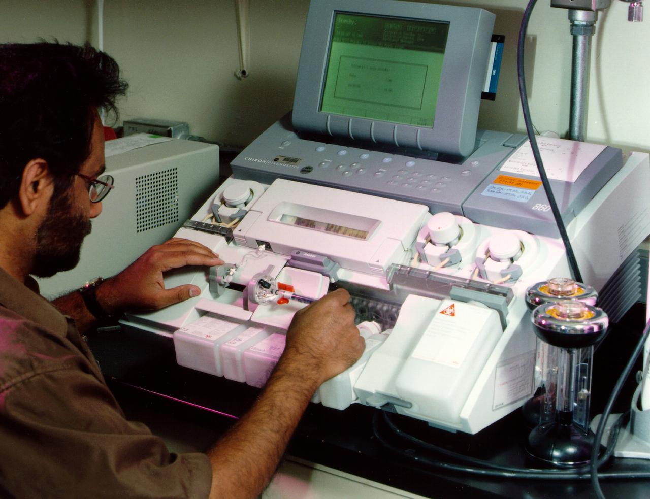 Dr. Harry Mahtani analyzes the gas content of nutrient media from Bioreactor used in research on human breast cancer. NASA's Marshall Space Flight Center (MSFC) is sponsoring research with Bioreactors, rotating wall vessels designed to grow tissue samples in space, to understand how breast cancer works. This ground-based work studies the growth and assembly of human mammary epithelial cells (HMEC) from breast cancer susceptible tissue. Radiation can make the cells cancerous, thus allowing better comparisons of healthy vs. tunourous tissues. 