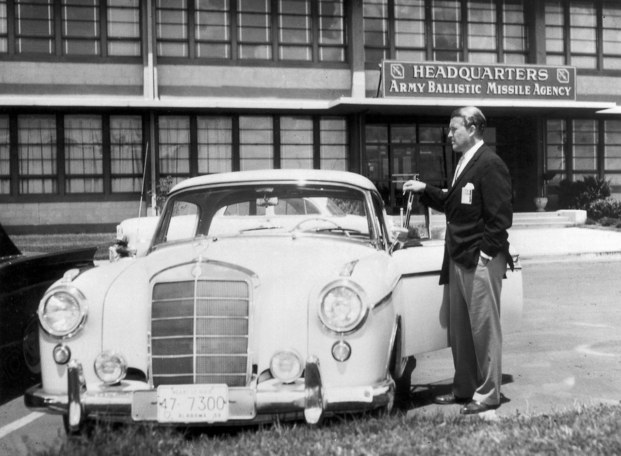 In this picture, Dr. Wernher von Braun, who was serving as Director of the Army Ballistic Missile Agency's (ABMA) Development Operations Division, is shown posed with his Mercedes 220SE automobile in front of Redstone Building 4488, which houses the ABMA.