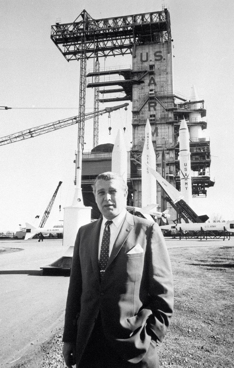 In this photo, Director of the US Army Ballistic Missile Agency (ABMA) Development Operations Division, Dr. Wernher von Braun, is standing before a display of Army missiles celebrating ABMA's Fourth Open House. The missiles in the background include (left to right) a satellite on a Juno II shroud with a Nike Ajax pointing left in front of a Jupiter missile. The Lacrosse is in front of the Juno II. The Nike Hercules points skyward in front of the Juno II and the Redstone.