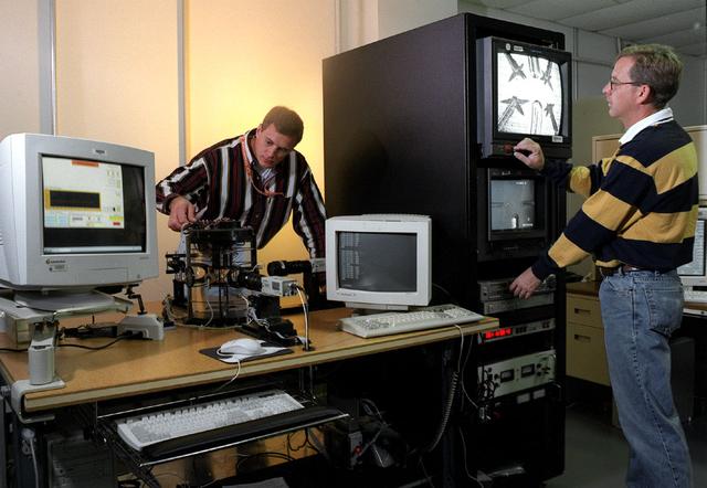 Test engineers, TK Pedergrass and Dave McIntosh, are growing multiple dendrites in an undercooled melt of ultra pure succinonitrile (SCN). Images and temperature measurements will give Dr. Christoph Beckerman, the EDSE Principal Investigator, information on the microstructural evolution of and thermal interactions between several equiaxed crystals growing dendritically. This benchmark data will be used to test and develop equiaxed dendritic solidification models. The monitors show both the 4 stinger and 2 stinger chambers that are placed in the isothermal bath for testing.