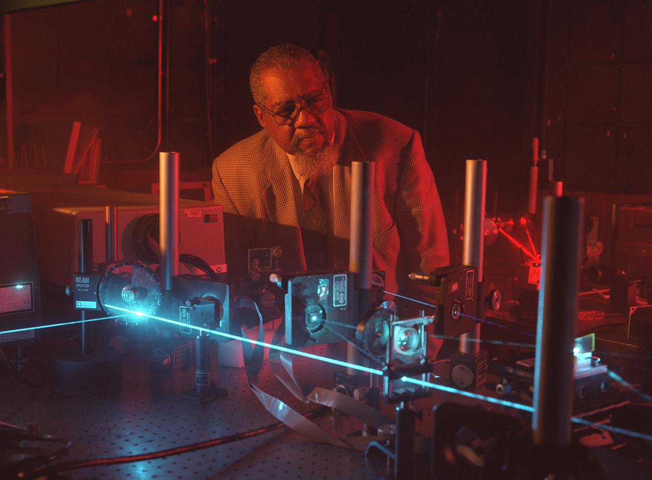 NASA researcher Dr. Donald Frazier uses a blue laser shining through a quartz window into a special mix of chemicals to generate a polymer film on the inside quartz surface. As the chemicals respond to the laser light, they adhere to the glass surface, forming optical films. Dr. Frazier and Dr. Mark S. Paley developed the process in the Space Sciences Laboratory at NASA's Marshall Space Flight Center in Huntsville, AL. Working aboard the Space Shuttle, a science team led by Dr. Frazier formed thin-films potentially useful in optical computers with fewer impurities than those formed on Earth. Patterns of these films can be traced onto the quartz surface. In the optical computers of the future, thee films could replace electronic circuits and wires, making the systems more efficient and cost-effective, as well as lighter and more compact. Photo credit: NASA/Marshall Space Flight Center