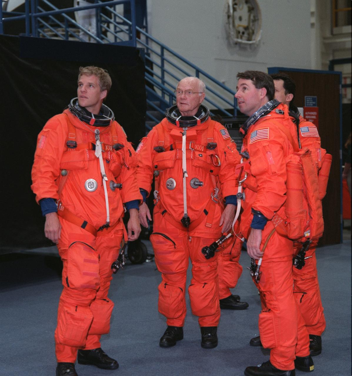 S98-07961 (5 June 1998) --- Four members of the STS-95 crew look on as a fifth crew member (out of frame) simulates emergency egress from a space shuttle during a training session in the systems integration facility at NASA's Johnson Space Center. Wearing training versions of the space shuttle partial pressure launch and entry suit are (from the left) Scott E. Parazynski, U.S. Sen. John H. Glenn Jr. (D.-Ohio), Stephen K. Robinson and Pedro Duque of the European Space Agency (ESA).