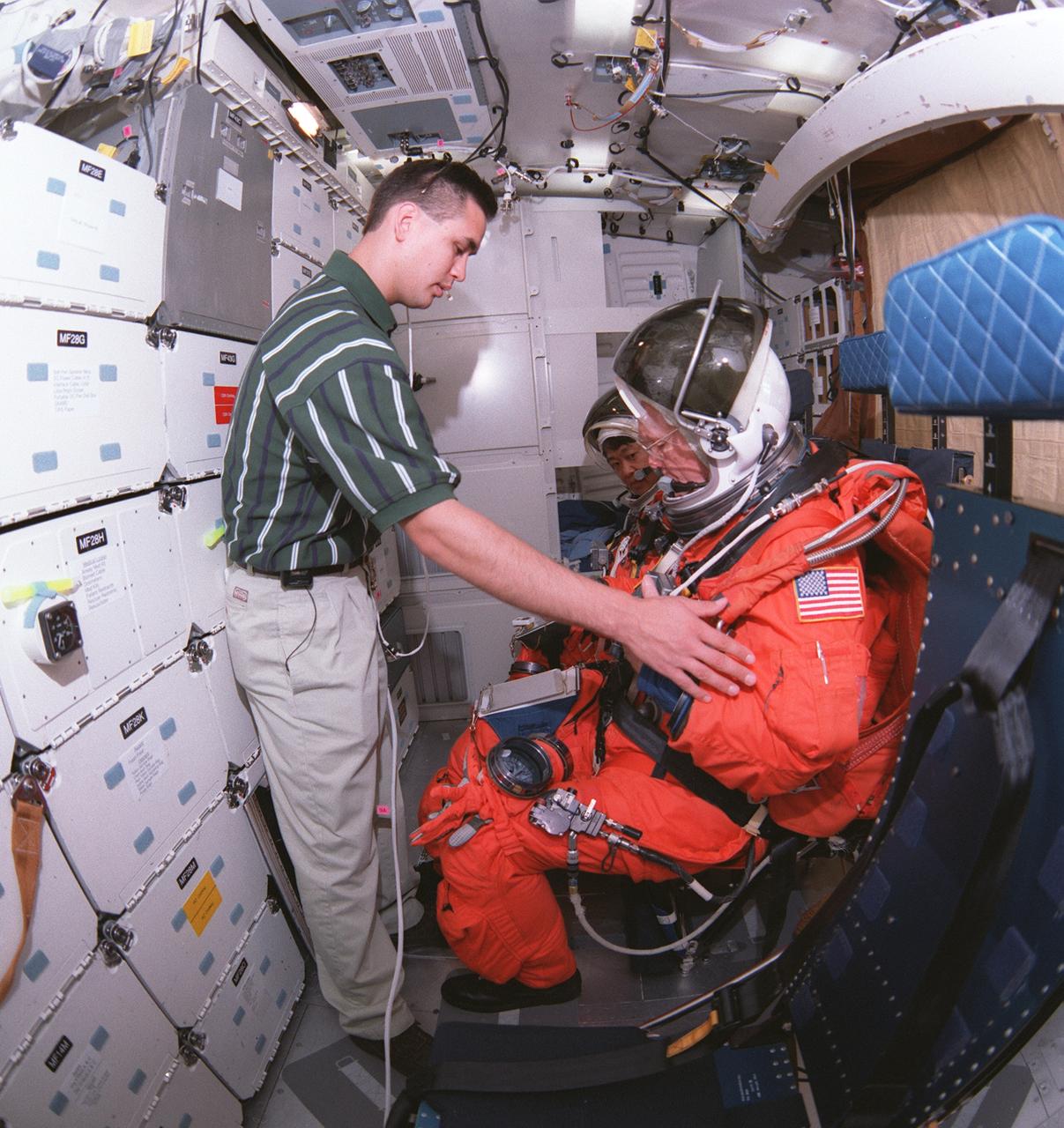 S98-07969 (5 June 1998) --- Crew trainer Adam Flagan (left) checks out STS-95 payload specialists Chiaki Naito-Mukai and John H. Glenn Jr. as they practice launch and entry procedures on the middeck of one of the training mockups in the Johnson Space Center's Space Vehicle Mockup Facility. The STS-95 mission, tentatively scheduled for launch on Oct. 29, will involve a variety of science experiments being carried in the pressurized Spacehab module, deployment and retrieval of the Spartan free-flyer payload, and operations with the HST Orbiting Systems Test and the International Extreme Ultraviolet Hitchhiker payloads.