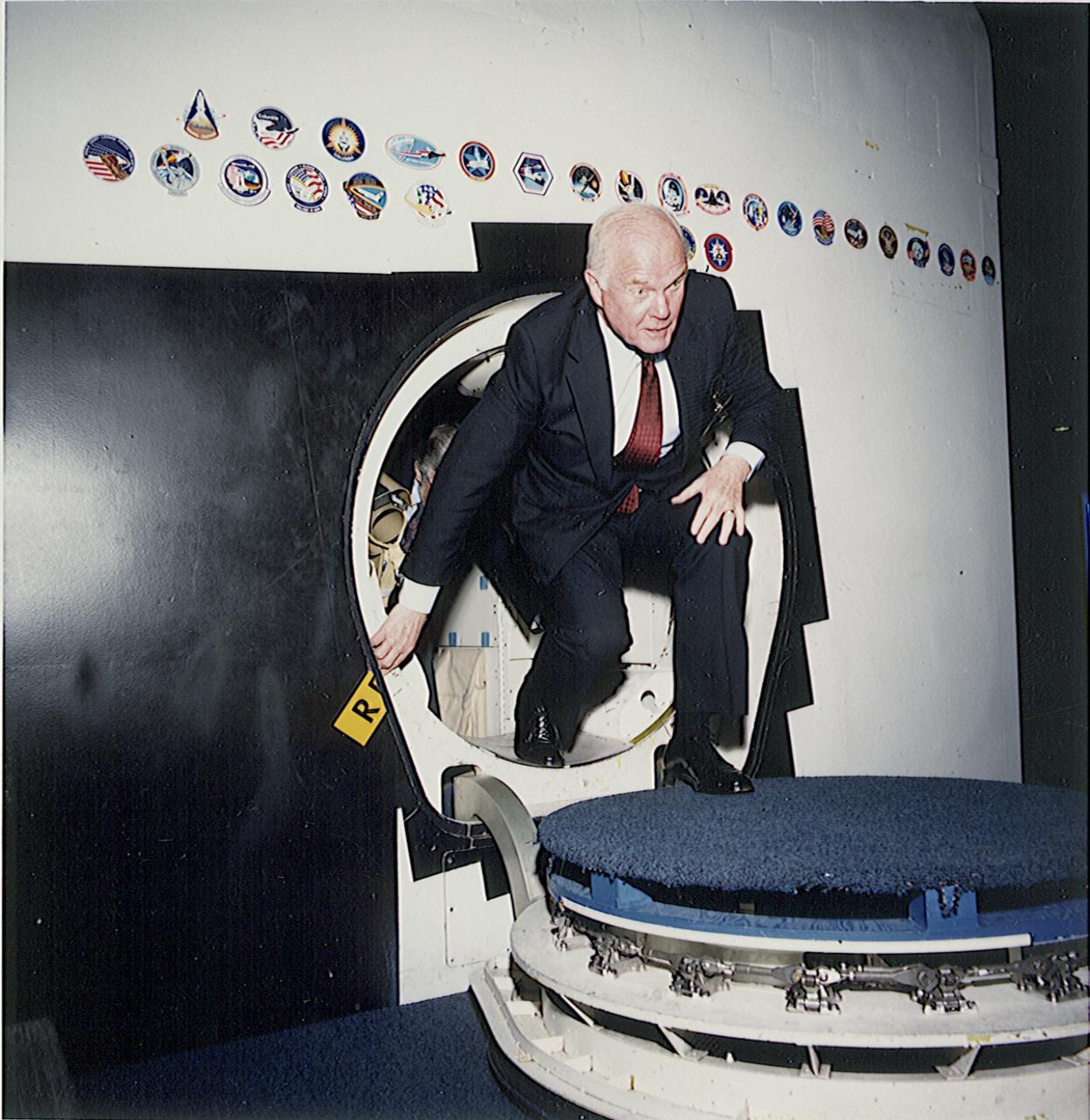 98-E-01183 (24 April 1989) -- U.S. Senator John H. Glenn Jr. (D., Ohio) egresses a shuttle trainer in the shuttle mockup and integration facility during a tour on April 24, 1989.