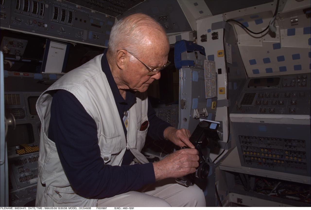 98-E-04411 (8 May 1998) --- U.S. Sen. John H. Glenn Jr., assigned as payload specialist aboard the Space Shuttle Discovery for NASA's STS-95 mission, checks a 35mm during a training session at the Johnson Space Center (JSC). He is on the flight deck of the full fuselage trainer (FFT) in the Systems Integration Facility.