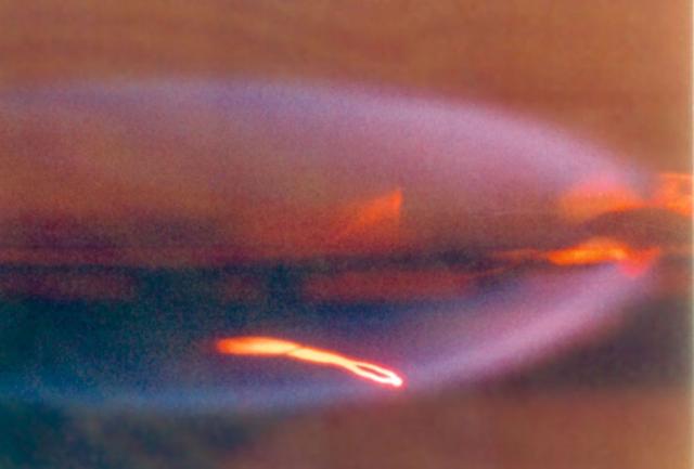 The Forced Flow Flame-Spreading Test was designed to study flame spreading over solid fuels when air is flowing at a low speed in the same direction as the flame spread. Previous research has shown that in low-speed concurrent airflows, some materials are more flammable in microgravity than earth. This image shows a 10-cm flame in microgravity that burns almost entirely blue on both sides of a thin sheet of paper. The glowing thermocouple in the lower half of the flame provides temperature measurements.