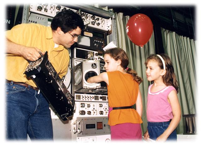 Glovebox Systems Engineer, Sam Ortega, explains how the microgravity glovebox works to 2 young MSFC Open House visitors.