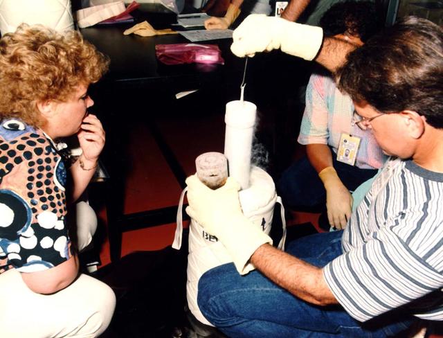Liquid nitrogen dewar loading at Kennedy Space Center for STS-71 flight with Stan Koszelak (right), University of California at Riverside, adn Tamara Chinareva (left), Russian Spacecraft Coporation-Energia. The picture shows Koszelak removing the insert from the transportation dewar.