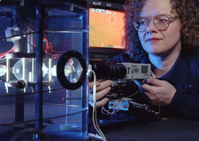 Jeri Briscoe of the video team inspects the optical system for proper alignment during a test run of the Equiaxed Dendritic Solidification Experiment (EDSE) located in the Microgravity Development Laboratory (MDL).