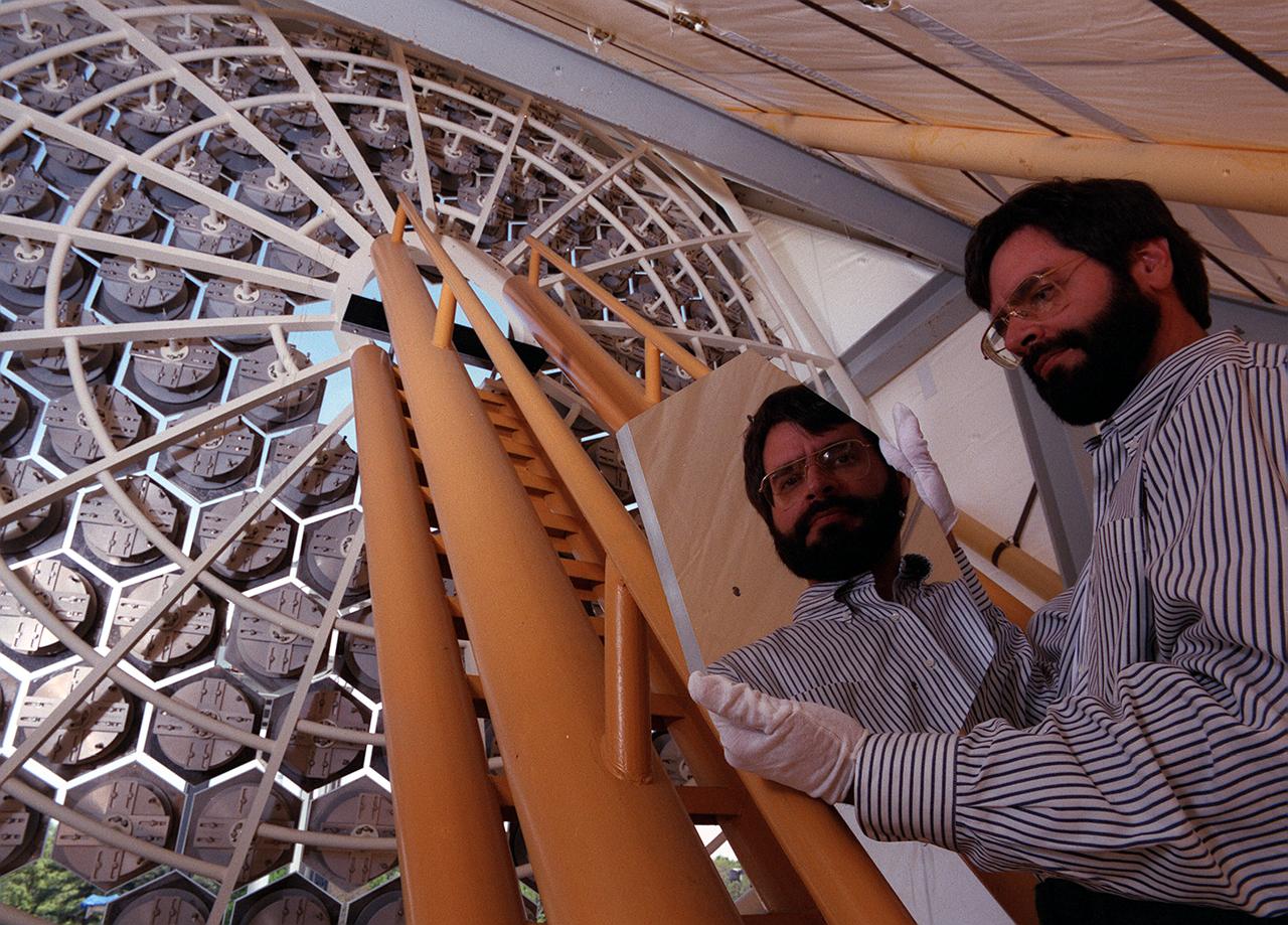 NASA's Space Optics Manufacturing Technology Center has been working to expand our view of the universe via sophisticated new telescopes. The Optics Center's goal is to develop low-cost, advanced space optics technologies for the NASA program in the 21st century, including the long-term goal of imaging Earth-like planets in distant solar systems. A segmented array of mirrors was designed by the Space Optics Manufacturing Technology Center for solar the concentrator test stand at the Marshall Space Flight Center (MSFC) for powering solar thermal propulsion engines. Each hexagon mirror has a spherical surface to approximate a parabolic concentrator when combined into the entire 18-foot diameter array. The aluminum mirrors were polished with a diamond turning machine, that creates a glass-like reflective finish on metal. The precision fabrication machinery at the Space Optics Manufacturing Technology Center at MSFC can polish specialized optical elements to a world class quality of smoothness. This image shows optics physicist, Vince Huegele, examining one of the 144-segment hexagonal mirrors of the 18-foot diameter array at the MSFC solar concentrator test stand.