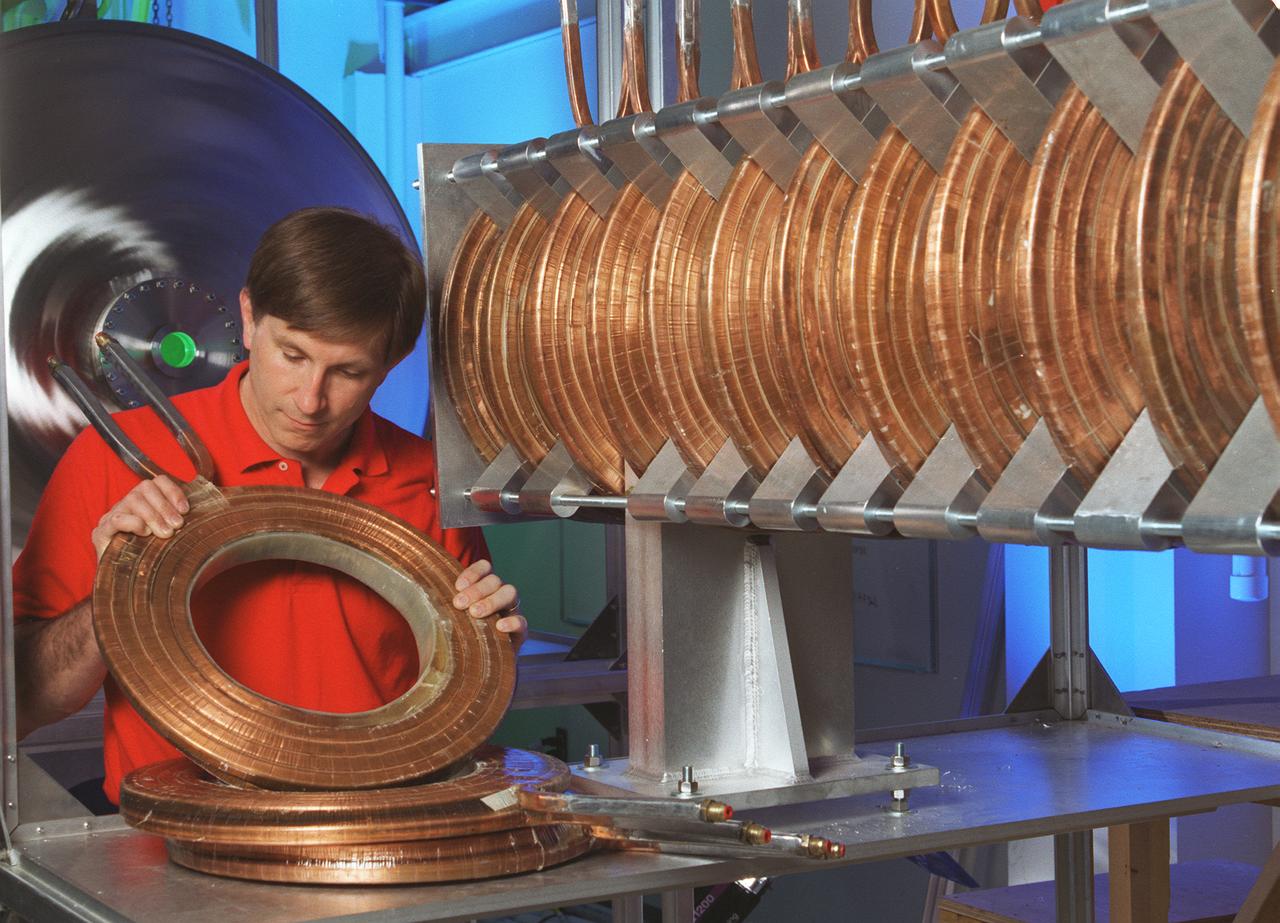 The Gasdynamic Mirror, or GDM, is an example of a magnetic mirror-based fusion propulsion system. Its design is primarily consisting of a long slender solenoid surrounding a vacuum chamber that contains plasma. The bulk of the fusion plasma is confined by magnetic field generated by a series of toroidal-shaped magnets in the center section of the device. the purpose of the GDM Fusion Propulsion Experiment is to confirm the feasibility of the concept and to demonstrate many of the operational characteristics of a full-size plasma can be confined within the desired physical configuration and still reman stable. This image shows an engineer from Propulsion Research Technologies Division at Marshall Space Flight Center inspecting solenoid magnets-A, an integrate part of the Gasdynamic Mirror Fusion Propulsion Engine Experiment.