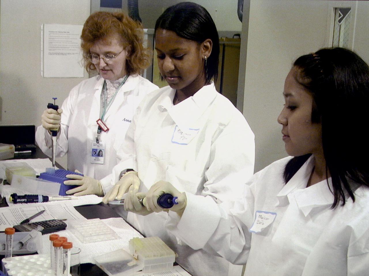 Chemist Arna Holmes, left, from the University of Alabama in Huntsville, teaches NaLonda Moorer, center, and Maricar Bana, right, both from Terry Parker High School in Jacksonville, Fl, procedures for preparing protein crystal growth samples for flight aboard the International Space Station (ISS). NASA/Marshall Space Flight Center in Huntsville, AL, is a sponsor for this educational activity. The proteins are placed in plastic tubing that is heat-sealed at the ends, then flash-frozen and preserved in a liquid nitrogen Dewar. Aborad the ISS, the nitrogen will be allowed to evaporated so the samples thaw and then slowly crystallize. They will be analyzed after return to Earth. Photo credit: NASA/Marshall Space Flight Center (MSFC)