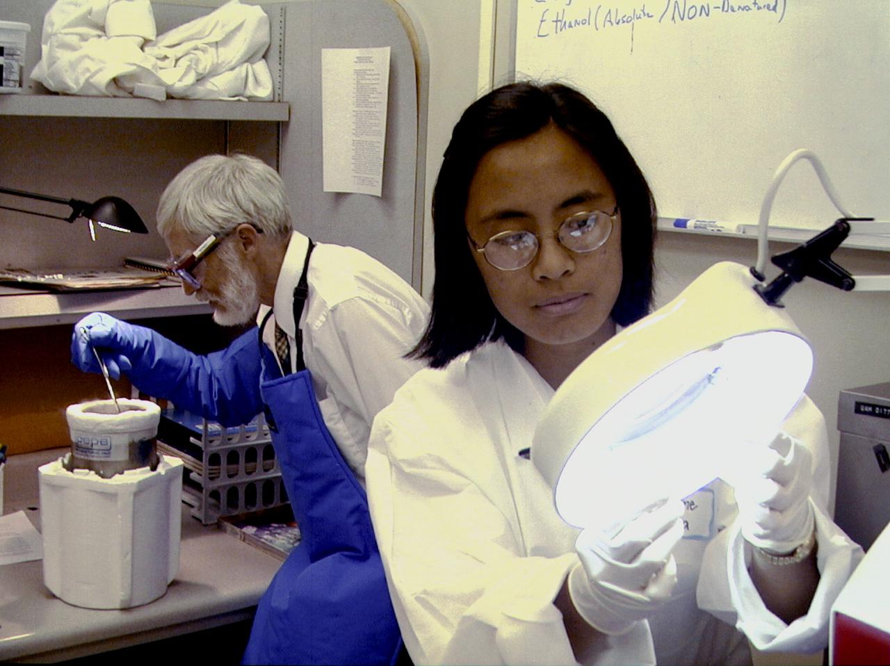 Christiane Gumera, right, a student at Stanton College Preparatory High School in Jacksonville, AL, examines a protein sample while preparing an experiment for flight on the International Space Station (ISS). Merle Myers, left, a University of California, Irvine, researcher, prepares to quick-freeze protein samples in nitrogen. The proteins are in a liquid nitrogen Dewar. Aboard the ISS, the nitrogen will be allowed to evaporated so the samples thaw and then slowly crystallize. They will be anlyzed after return to Earth. Photo credit: NASA/Marshall Space Flight Center (MSFC)
