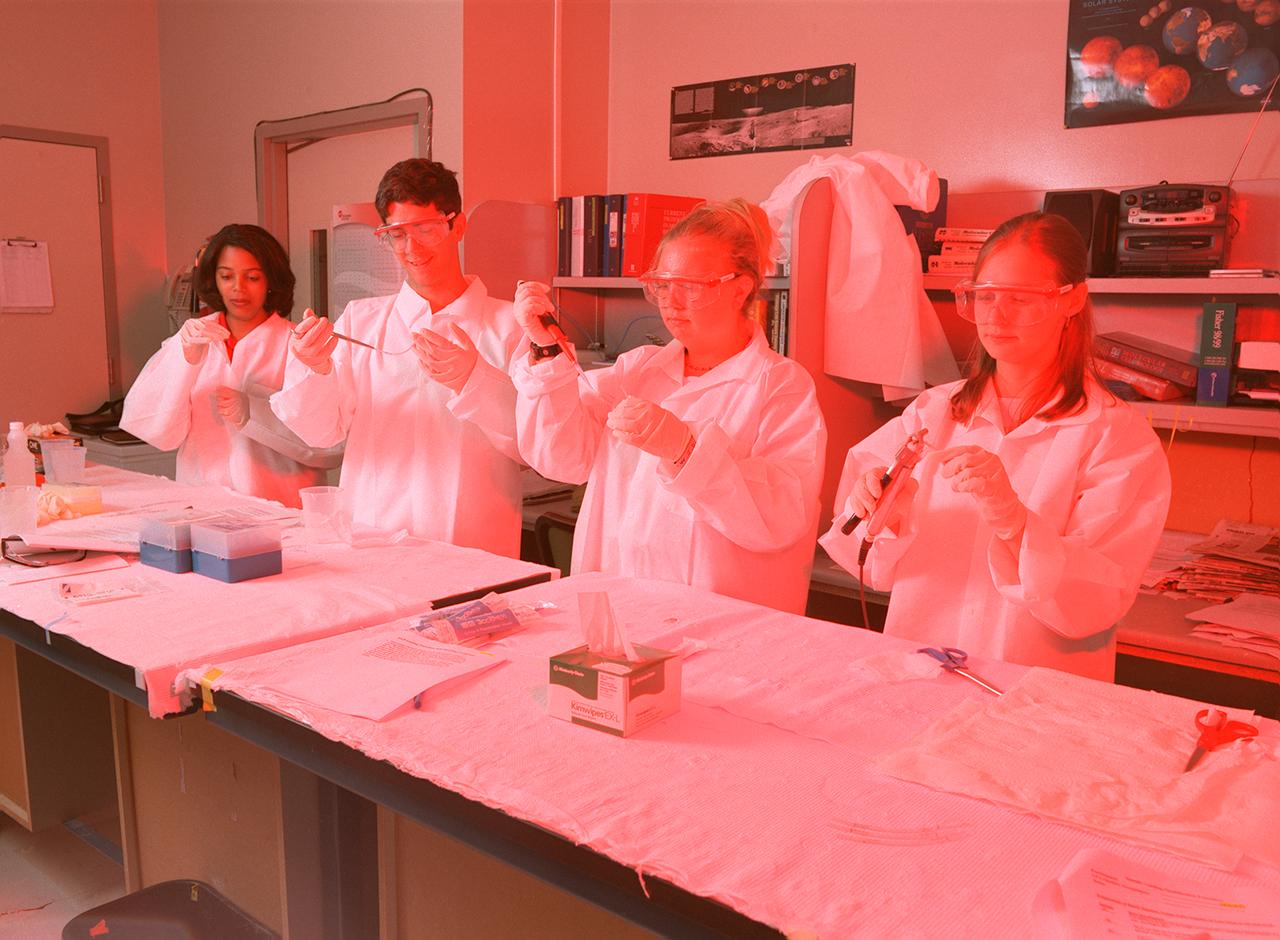 Memphis students working at the University of Alabama in Huntsville prepare samples for the first protein crystal growth experiments plarned to be performed aboard the International Space Station (ISS). The proteins are placed in plastic tubing that is heat-sealed at the ends, then flash-frozen and preserved in a liquid nitrogen Dewar. Aboard the ISS, the nitrogen will be allowed to evaporated so the samples thaw and then slowly crystallize. They will be analyzed after return to Earth. Photo credit: NASA/Marshall Space Flight Center (MSFC)