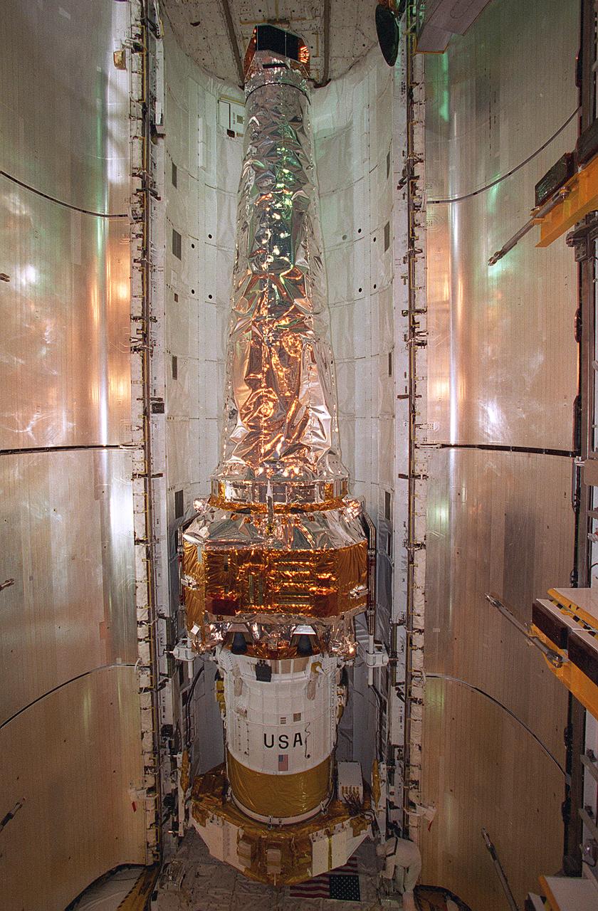 In this photograph, the Chandra X-Ray Observatory (CXO) was installed and mated to the Inertial Upper Stage (IUS) inside the Shuttle Columbia's cargo bay at the Kennedy Space Center. The CXO will help astronomers world-wide better understand the structure and evolution of the universe by studying powerful sources of x-rays such as exploding stars, matter falling into black holes, and other exotic celestial objects. X-ray astronomy can only be done from space because Earth's atmosphere blocks x-rays from reaching the surface. The Observatory provides images that are 50 times more detailed than previous x-ray missions. At more than 45 feet in length and weighing more than 5 tons, the CXO was carried into low-Earth orbit by the Space Shuttle Columbia (STS-93 mission) on July 22, 1999. The Observatory was deployed from the Shuttle's cargo bay at 155 miles above the Earth. Two firings of an attached IUS rocket, and several firings of its own onboard rocket motors, after separating from the IUS, placed the Observatory into its working orbit. The IUS is a solid rocket used to place spacecraft into orbit or boost them away from the Earth on interplanetary missions. Since its first use by NASA in 1983, the IUS has supported a variety of important missions, such as the Tracking and Data Relay Satellite, Galileo spacecraft, Magellan spacecraft, and Ulysses spacecraft. The IUS was built by the Boeing Aerospace Co., at Seattle, Washington and managed by the Marshall Space Flight Center.