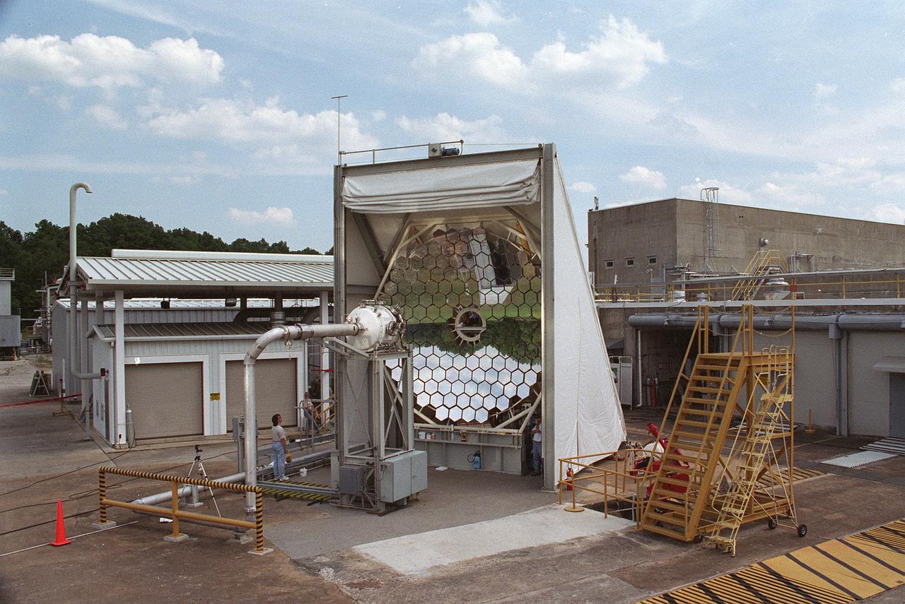 Researchers at the Marshall Space Flight Center (MSFC) have designed, fabricated and tested the first solar thermal engine, a non-chemical rocket engine that produces lower thrust but has better thrust efficiency than a chemical combustion engine. MSFC turned to solar thermal propulsion in the early 1990s due to its simplicity, safety, low cost, and commonality with other propulsion systems. Solar thermal propulsion works by acquiring and redirecting solar energy to heat a propellant. This photograph, taken at MSFC's Solar Thermal Propulsion Test Facility, shows a concentrator mirror, a combination of 144 mirrors forming this 18-ft diameter concentrator, and a vacuum chamber that houses the focal point. The 20- by 24-ft heliostat mirror (not shown in this photograph) has a dual-axis control that keeps a reflection of the sunlight on the 18-foot diameter concentrator mirror, which then focuses the sunlight to a 4-in focal point inside the vacuum chamber. The focal point has 10 kilowatts of intense solar power. As part of MSFC's Space Transportation Directorate, the Propulsion Research Center serves as a national resource for research of advanced, revolutionary propulsion technologies. The mission is to move the Nation's capabilities beyond the confines of conventional chemical propulsion into an era of aircraft-like access to Earth-orbit, rapid travel throughout the solar system, and exploration of interstellar space.