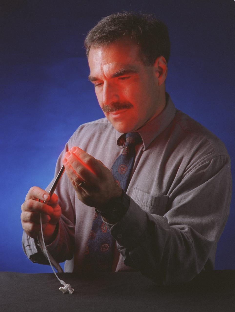 The red light from the Light Emitting Diode (LED) probe shines through the fingers of Dr. Harry Whelan, a pediatric neurologist at the Children's Hospital of Wisconsin in Milwaukee. Dr. Whelan uses the long waves of light from the LED surgical probe to activate special drugs that kill brain tumors. Laser light previously has been used for this type of surgery, but the LED light illuminates through all nearby tissues, reaching parts of tumors that shorter wavelengths of laser light carnot. The new probe is safer because the longer wavelengths of light are cooler than the shorter wavelengths of laser light, making the LED less likely to injure normal brain tissue near the tumor. Also, it can be used for hours at a time while still remaining cool to the touch. The probe was developed for photodynamic cancer therapy under a NASA Small Business Innovative Research Program grant. The program is part of NASA's Technology Transfer Department at the Marshall Space Flight Center.