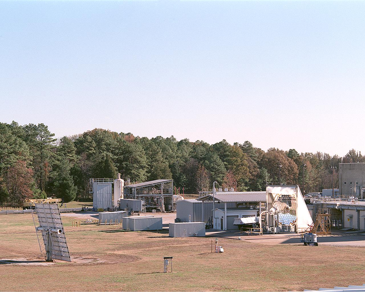 This photograph shows an overall view of the Solar Thermal Propulsion Test Facility at the Marshall Space Flight Center (MSFC). The 20-by 24-ft heliostat mirror, shown at the left, has dual-axis control that keeps a reflection of the sunlight on an 18-ft diameter concentrator mirror (right). The concentrator mirror then focuses the sunlight to a 4-in focal point inside the vacuum chamber, shown at the front of concentrator mirror. Researchers at MSFC have designed, fabricated, and tested the first solar thermal engine, a non-chemical rocket engine that produces lower thrust but has better thrust efficiency than chemical a combustion engine. MSFC turned to solar thermal propulsion in the early 1990s due to its simplicity, safety, low cost, and commonality with other propulsion systems. Solar thermal propulsion works by acquiring and redirecting solar energy to heat a propell nt. As part of MSFC's Space Transportation Directorate, the Propulsion Research Center serves as a national resource for research of advanced, revolutionary propulsion technologies. The mission is to move the Nation's capabilities beyond the confines of conventional chemical propulsion into an era of aircraft-like access to Earth-orbit, rapid travel throughout the solar system, and exploration of interstellar space.