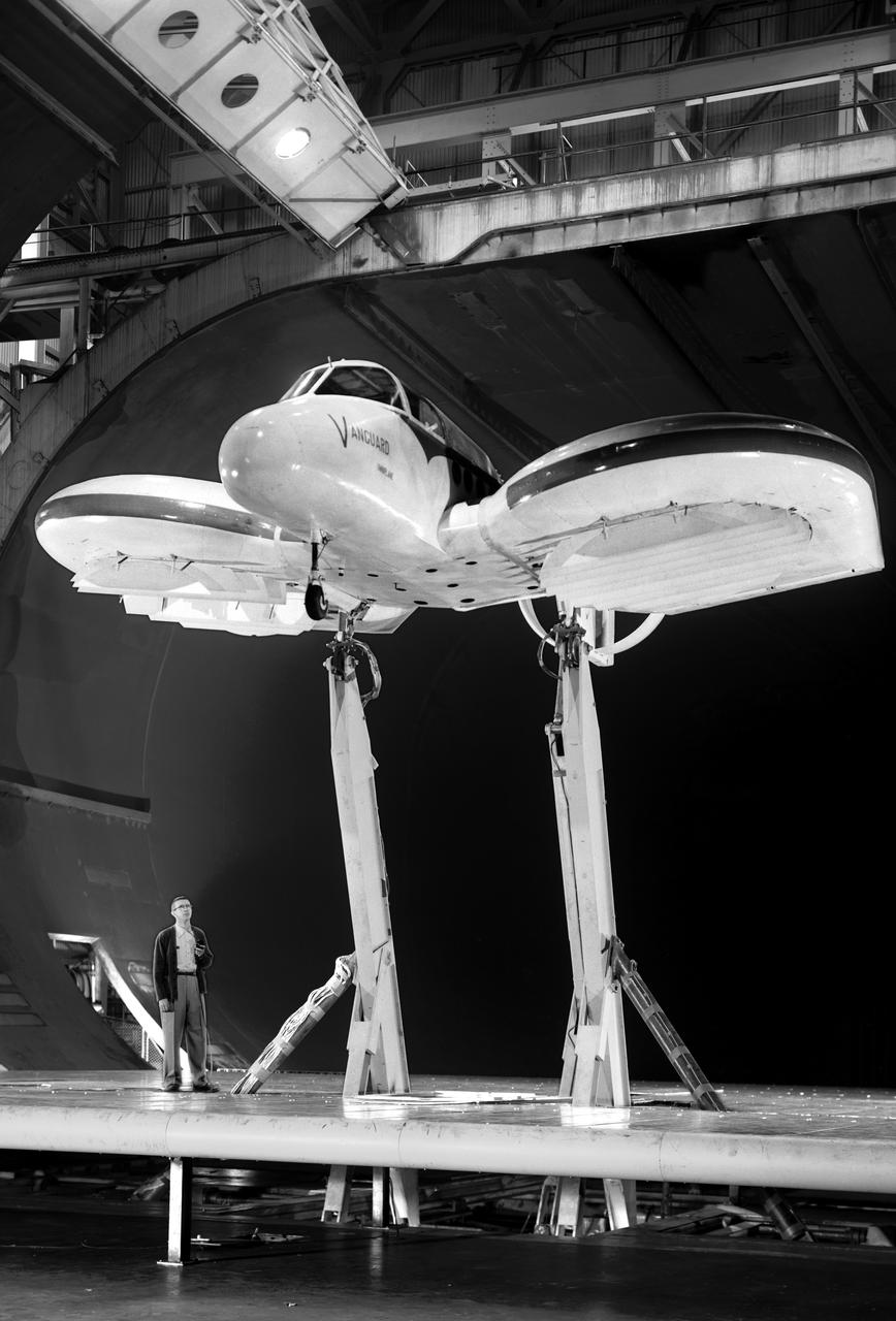 Vanguard 2C vertical take-off and landing (VTOL) airplane, wind tunnel test. Front view from below, model 14 1/2 feet high disk off. Nasa Ames engineer Ralph Maki in photo.  Variable height struts and ground plane, low pressure ratio, fan in wing.  02/01/1960.