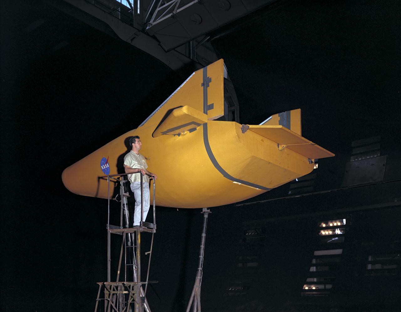 M-2 lifting body wind tunnel model with wind tunnel mechanic Chuck Greco.  Model mounted on special support designed for lifting body models.  Flaps and elevons visible.