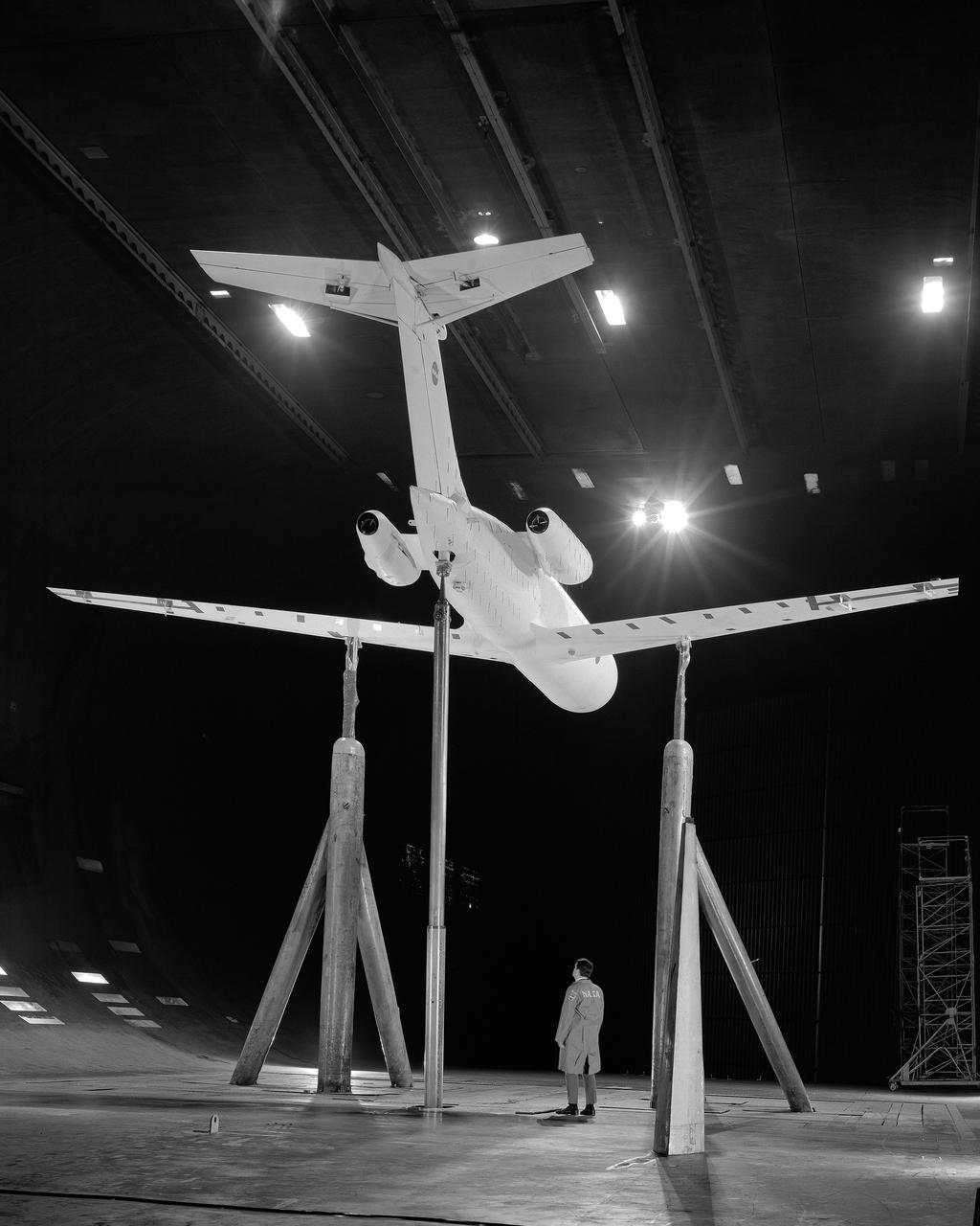 3/4 rear view from below of swept wing jet transport with T-Tail and Aft Engins, with Art Morris. Deep Stall Model in Ames 40x80 foot Wind Tunnel.