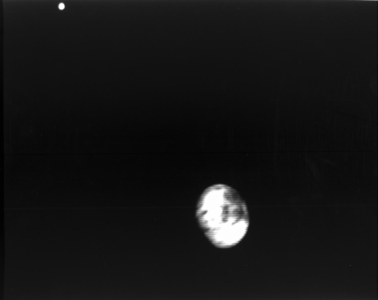 Range : 5.9 million kilometers (3.66 million miles) Europa is Jupiter's 2nd Galilean satellites from the planet and the brightest.  Photo taken early morning through violet filter.  Faint swirls and linear patterns show in the equatorial region (which shows darker than the poles).  This hemisphere always faces Jupiter.    North is up.  Density and size comparable to Earth's Moon and seems to show water ice or ground water on its surface.   JPL Reference # P-21163.