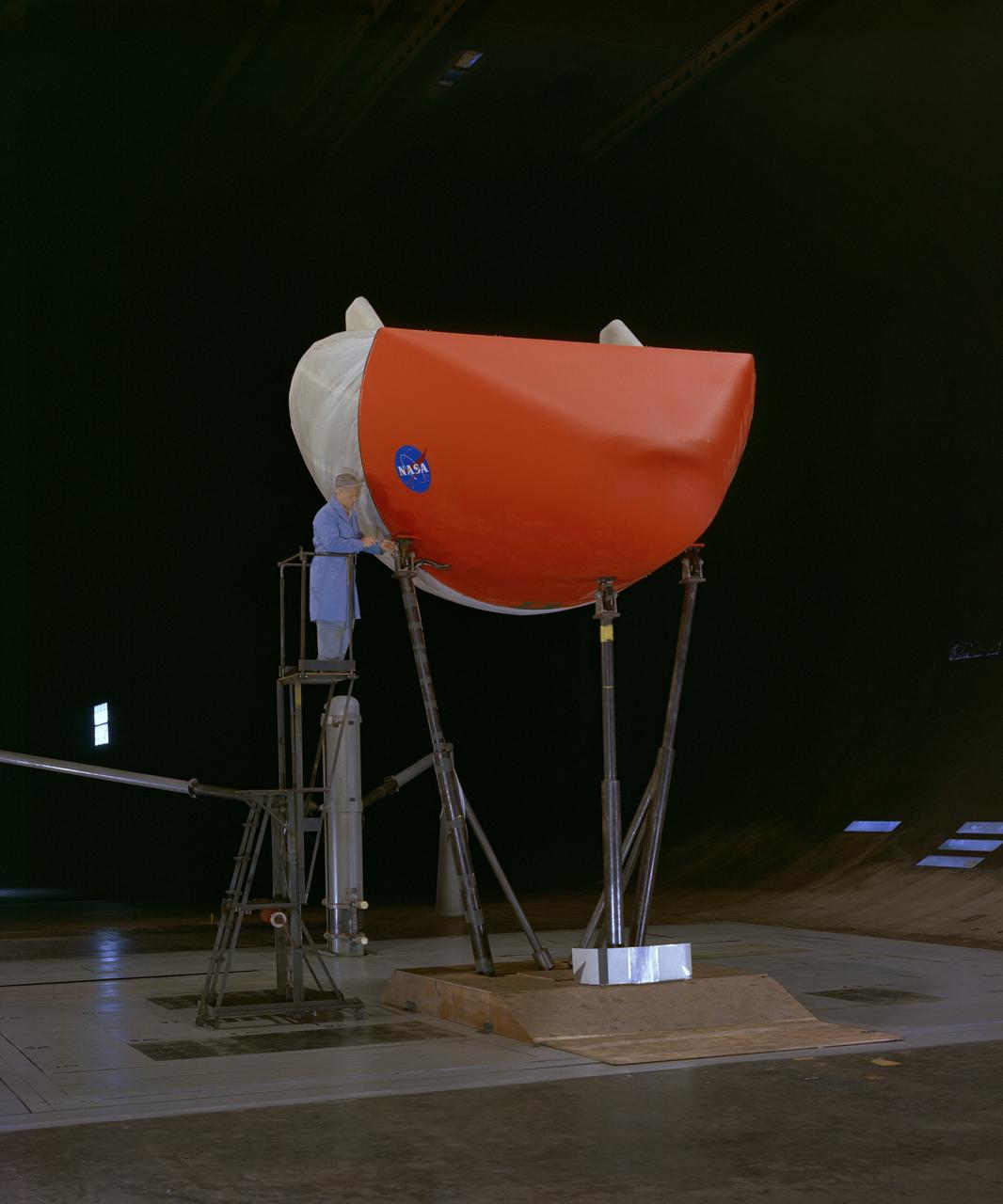 3/4 front view of M-1-L inflatable recovery able lifting body model in Ames 40x80 foot wind tunnel. Mechanic, Ray Schmorance included in picture.
