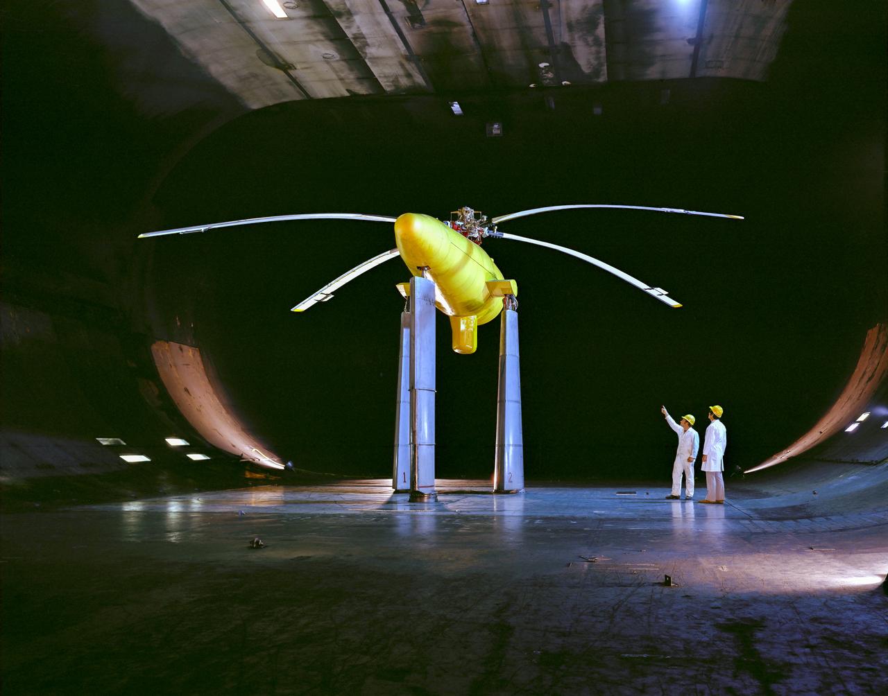 3/4 lower rear view of Controllable Twist Rotor (CTR) test of 4 blade helicopter model. Pictures with Ben Mandwyler Andy Lemnios, in 40x80 foot wind tunnel. Small flaps on rotor blades.