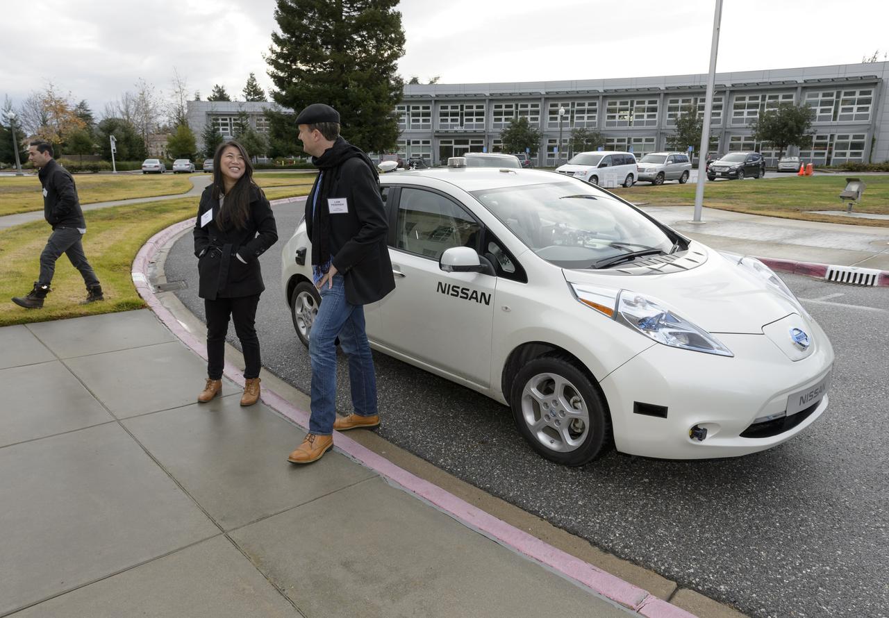 This Nissan LEAF vehicle being tested on the Ames campus is equipped with cameras, sensors and cellular data networking, and uses robotics software originally developed for Ames’ K-10 and K-REX planetary rovers to operate autonomously.  Shown here are Kathy Sun and Liam Pedersen, Nissan who are awaiting the arrival of the visiting group from Renault-Nissan Alliance for a demo ride across Ames.