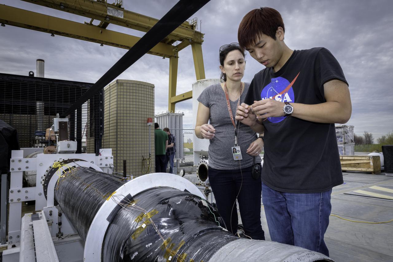 Ashley Karp, NASA JPL (Left) and Hunjoo Kim, NASA JPL (Right) attaching heat sensors the Peregrine Hybrid Rocket Engine prior to its test at the Outdoor Aerodynamic Research Facility (OARF, N-249) at NASA's Ames Research Center.