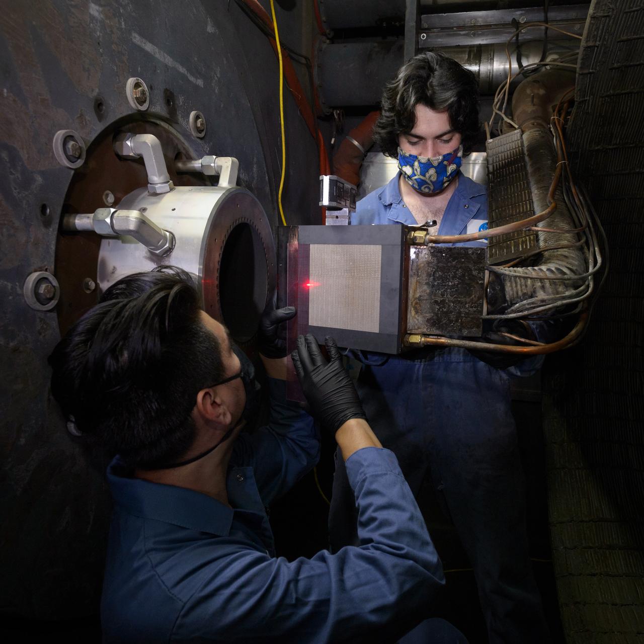Engineering technicians Pedro Solano, left, and Aaron Poulin, right, verify alignment of an Orion heat shield test article in the Arc Jet Interaction Heating Facility, or IHF, test section. This test of Orion’s heat shield using a combination of the IHF and the Laser Enhanced Arc Jet Facility, or LEAF-Lite, capabilities will certify the heat shield for the Artemis I and Artemis II missions. This is also the first time the heat shield is tested in an environment combining the two forms of heating, radiant and convective, the spacecraft will experience on entering Earth’s atmosphere.
