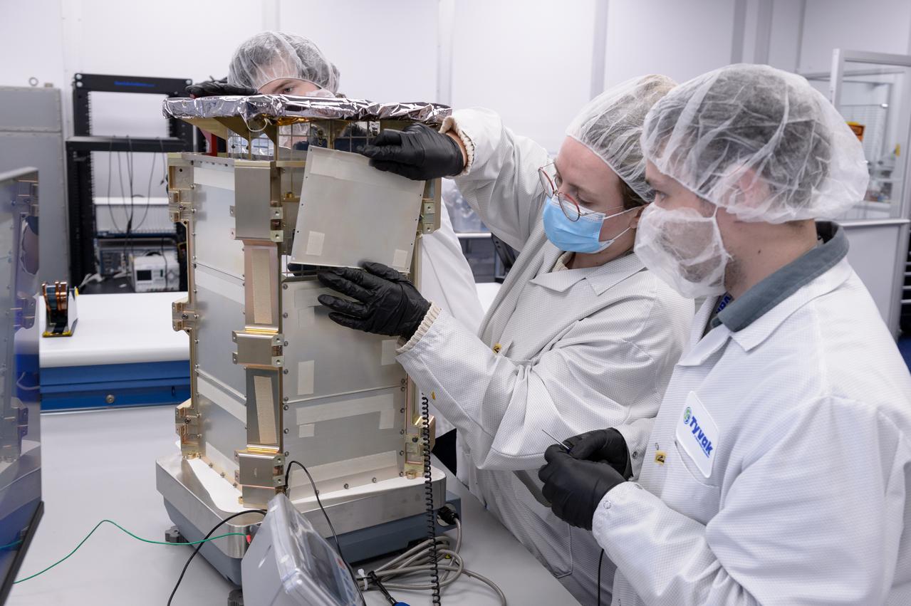 Rebecca Rogers, systems engineer, left, and Dustin Holta, launch engineer, right, mount a cover plate to the CAPSTONE spacecraft dispenser with the spacecraft stowed inside at Tyvak Nano-Satellite Systems, Inc., in Irvine, California.