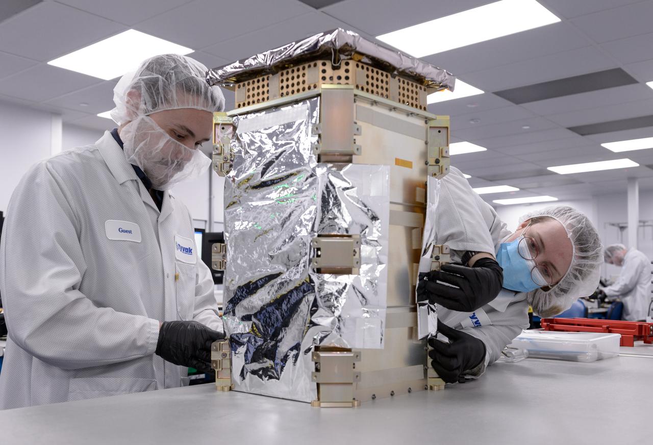 Dustin Holta, launch engineer, left, and Rebecca Rogers, systems engineer, right, wrap the CAPSTONE spacecraft dispenser in a thermal blanket with the spacecraft stowed inside at Tyvak Nano-Satellite Systems, Inc., in Irvine, California.
