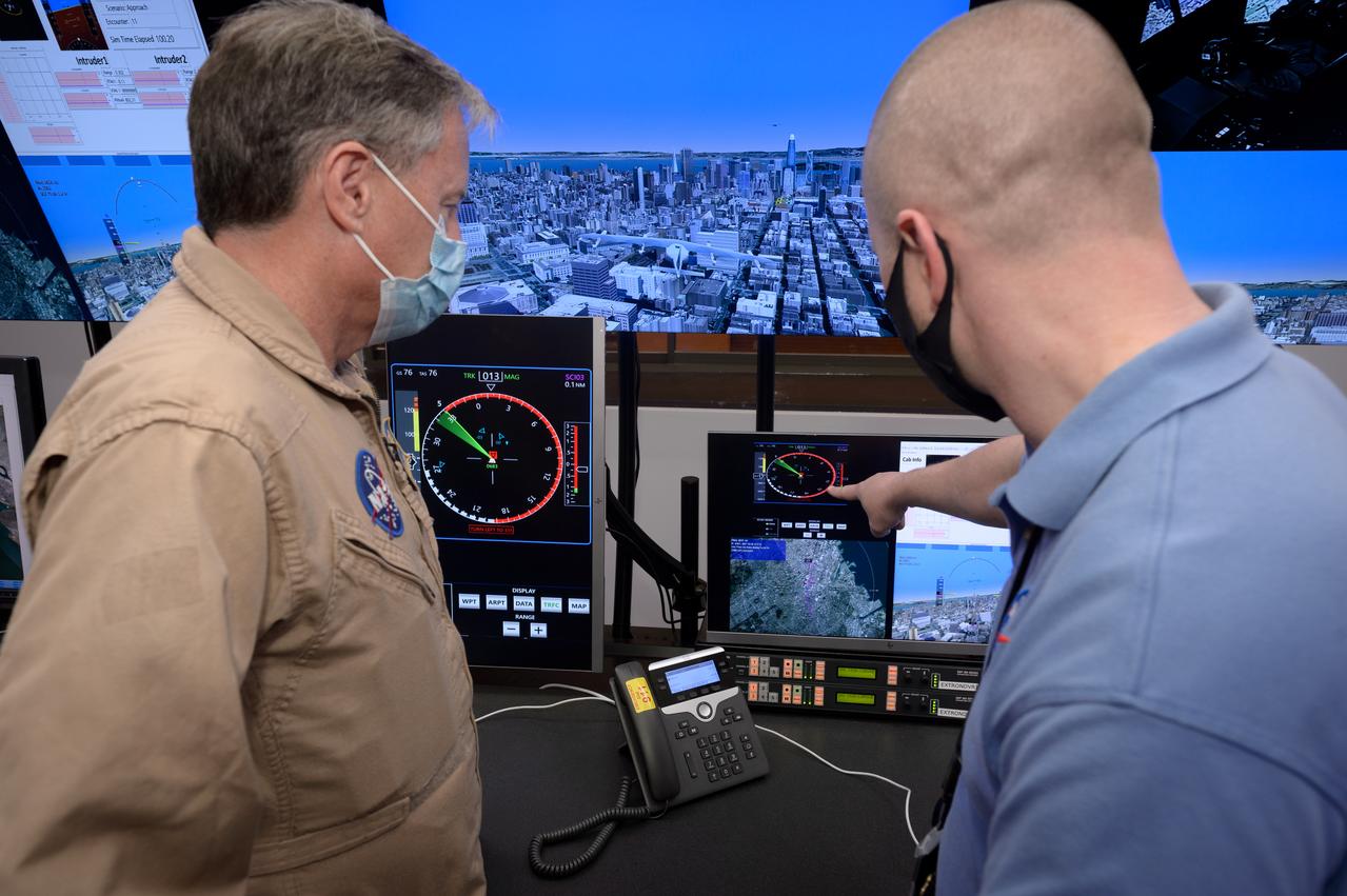 Human factors engineer Casey Smith, right, and pilot Wayne Ringelberg, left, discuss simulation results during a flight debrief in the VMS control room, N243.
