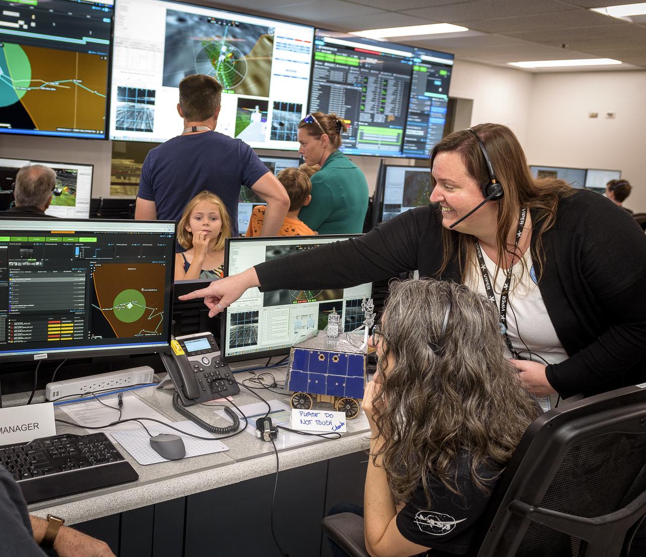 Kelsey Herrmann, right, reviewing the flight control display in the Multi-Mission Operations Center (MMOC), N240, for the Volatiles Investigating Polar Exploration Rover (VIPER) to Rachel Hoover during VIPER Family Day.