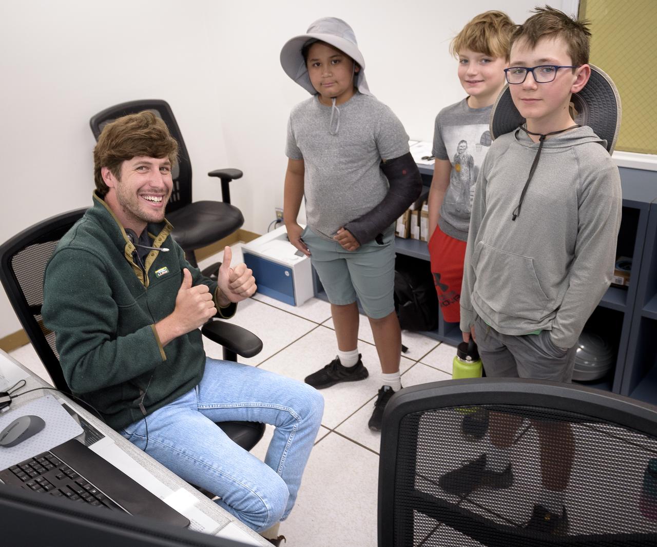 Jasper Wolfe, left, explains the Volatiles Investigating Polar Exploration Rover (VIPER) mission to visitors in the Multi-Mission Operations Center (MMOC), N240, for VIPER Family Day.
