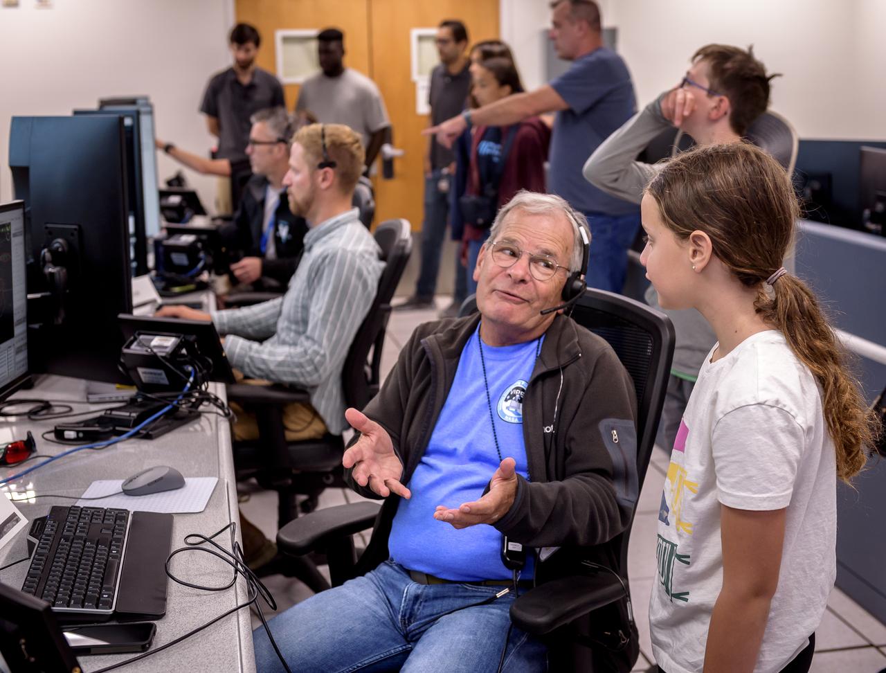 Rick Elphic, NSS instrument principal investigator, left, explains the Volatiles Investigating Polar Exploration Rover (VIPER) mission to visitors in the Multi-Mission Operations Center (MMOC), N240, during VIPER Family Day.